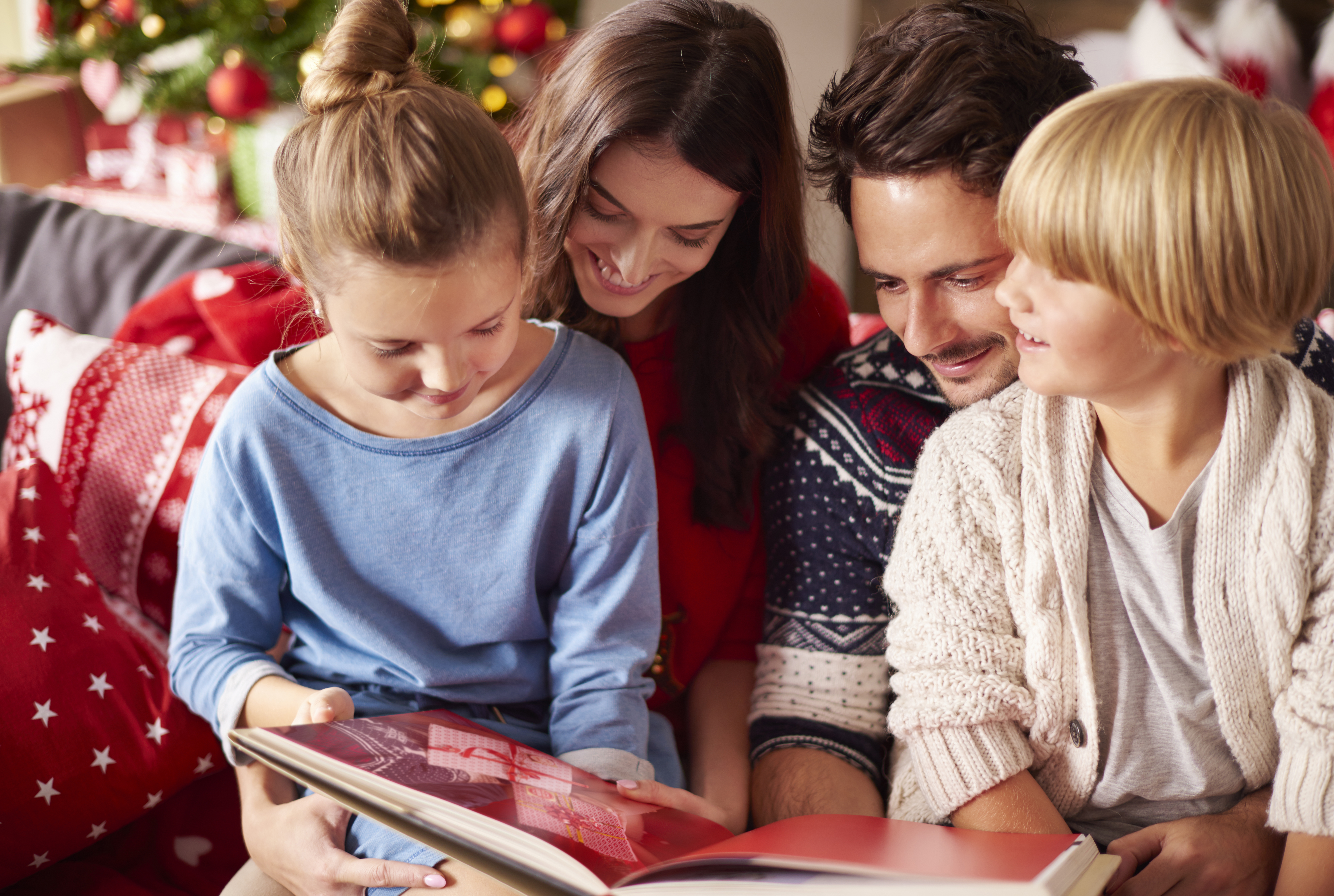 Couple avec ses deux enfants qui lisent un livre jeunesse